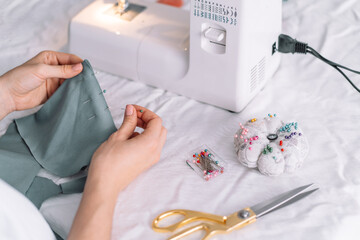 Lady fixes fabric with needles in front of a sewing machine.
