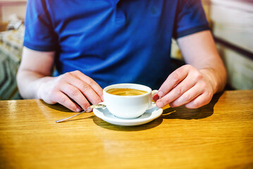A man drinks coffee at a table in a cafe
