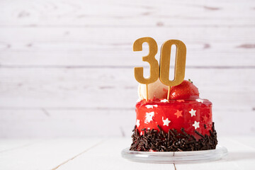 The number Thirty on a red birthday cake on a light background