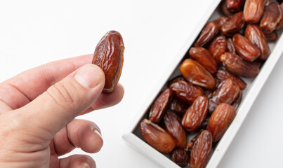 Dried date in hand isolated on white background.