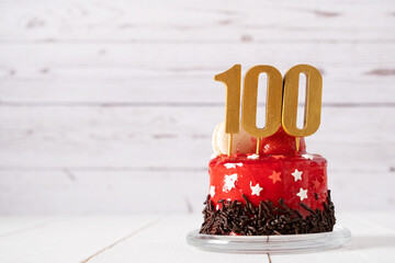 The number Hundred on a red birthday cake on a light background