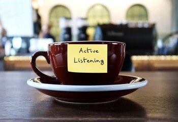 Coffee cup with label ACTIVE LISTENING, concept of improve listening skill, hear what people are really saying for job effectiveness or better relationships with others