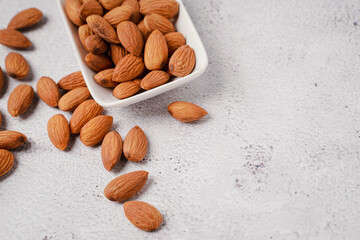 Almonds in white porcelain bowl on white table. Almond concept with copyspace.