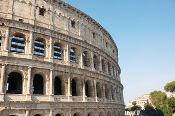 Fototapeta premium Coliseum (Colosseum), Rome, Italy. Ancient Roman Coliseum is famous landmark, top tourist attraction of Rome. Scenic view of Coliseum with blue sky.