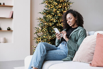 Young woman using smartphone at home during Christmas holiday, Student girl texting on mobile phone...