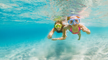 Young mother with child in snorkeling mask dive in coral reef sea lagoon to explore underwater...