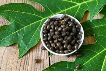 papaya seed and leaf leaves from papaya tree, papaya seeds on bowl on wooden backgroud