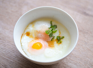 soft-boiled eggs on white bowl with pepper coriander on wooden table, egg breakfast, onsen egg