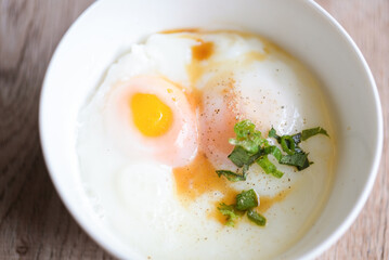 soft-boiled eggs on white bowl with pepper coriander on wooden table, egg breakfast, onsen egg
