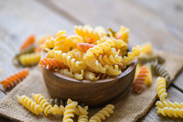 Pasta raw macaroni on wooden bowl background, close up raw macaroni spiral pasta uncooked delicious whole grain fusilli pasta for cooking food