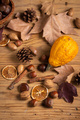 Overhead view of dried fruits, pumpkin and cinnamon with autumn leaves on wooden table, vertical