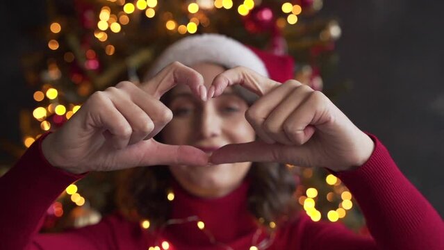 white woman face view through heart shape joined fingers, blogger share love