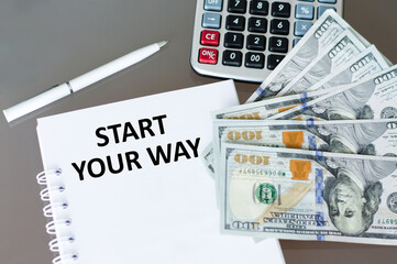 Start Your Way text on a notepad next to a pen, calculator and dollar bills on the table