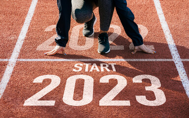 happy new year 2023 symbolizes the start of the new year. Rear view of a man preparing to run on the athletics track engraved with the year 2023. The goal of Success.Getting ready for the new year