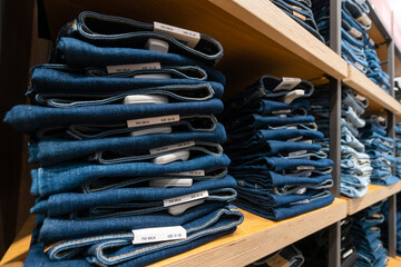 Close-up of a lot of jeans on the shelves in the store. Stack of jeans on the shelf. Concept of buying, selling, shopping and denim fashion.