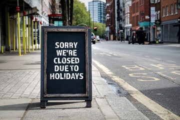 Sorry we're CLOSED due to HOLIDAYS. Foldable advertising poster on the street