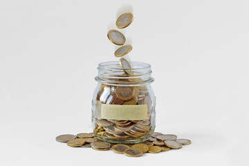 Money jar with blank label and falling coins on white background - Concept of economy and finance