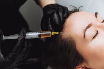 Plasma injection into the hair on a woman 's head .a cosmetologist makes plasma injections into the scalp
