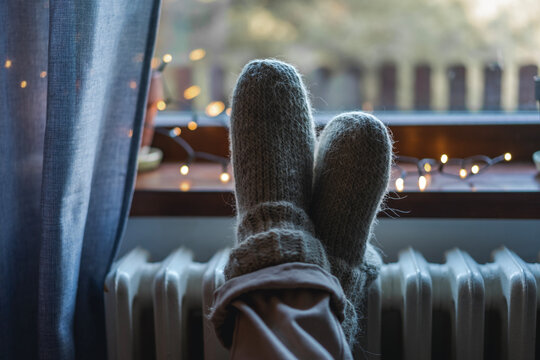 Women's legs feet in woolen socks on a heating battery