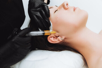 A cosmetologist performs plasmolifting on the face of a beautiful woman in a beauty salon. The concept of cosmetology.