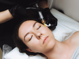 A cosmetologist performs plasmolifting on the face of a beautiful woman in a beauty salon. The...
