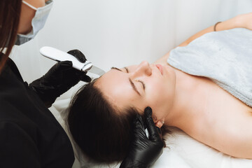 Obraz na płótnie Canvas Skin care. Close-up Of A Beautiful Woman Receiving An Ultrasound Facial Peeling. Ultrasonic skin cleaning procedure. Cosmetic procedures. Cosmetology.