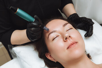 Cosmetic mesotherapy for facial rejuvenation. Cosmetic procedure of microneedling. The cosmetologist injects hyaluronic acid into the face of the girl's patient with the help of dermopen.