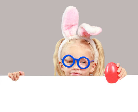 Cute happy girl with easter eggs and bunny ears holding a white lsit for inscriptions, empty space, easter composition, religious holidays concept, spring mood, isolated.