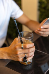 Hand with rings holding glass with straws
