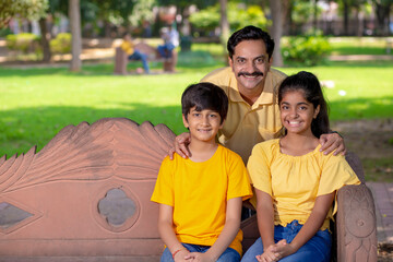 Happy Indian father with his daughter and son at park