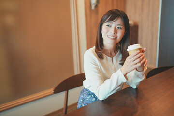 オフィスでコーヒーを飲みながら休憩する女性社員