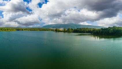 Lake covered with vegetation against backdrop of Rhodope mountains and clouds. Panorama, top view