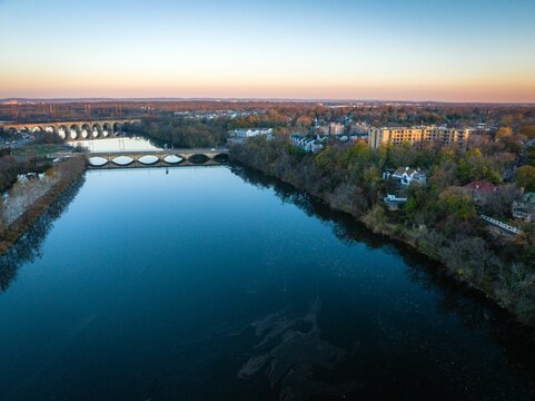 Fototapeta Drone view of a river with a bridge surrounded by buildings in New Brunswick, Rutgers, Hub City, USA