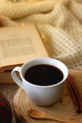 Cup of tea or coffee, seasonal spices, bowl of cookies, blanket, pumpkins, colorful leaves, books and tangerines on wooden table. Cozy hygge at home. Selective focus.