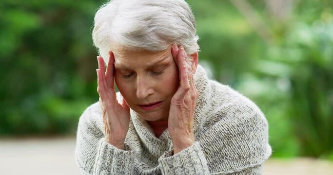 Stress, headache and senior woman in park for mental health, Alzheimer and sad. Depression, fatigue and retirement with face of elderly lady thinking in nature about cancer, burnout and anxiety