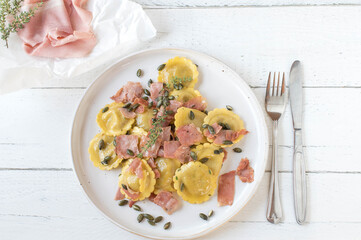 Filled pasta with italian ham, butter and roasted pumpkin seeds on a plate