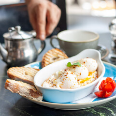Poached eggs on top of garlic yogurt with chili pepper sauce served with sourdough bread