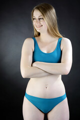 Cheerful happy young woman posing in blue bikini in studio