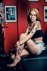 Fototapeta na wymiar Portrait of a girl with a tattoo on her shoulder in a modern studio lowlight.
