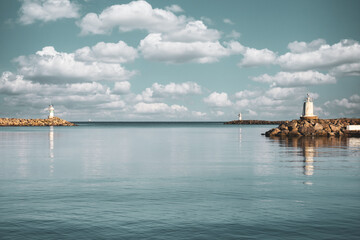 Two lighthouses facing each other in the port with clear sky and clouds. Clouds over the pier and...