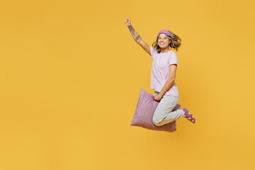 Full body young woman she wear purple pyjamas jam sleep eye mask rest relax at home jump high sit on pillow pov flying like witch isolated on plain yellow background studio portrait Night nap concept