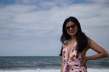 South American woman, young and beautiful, brunette with sunglasses and swimsuit posing happily on the beach. Concept sea, sand, sun, beach, vacation, travel, summer.