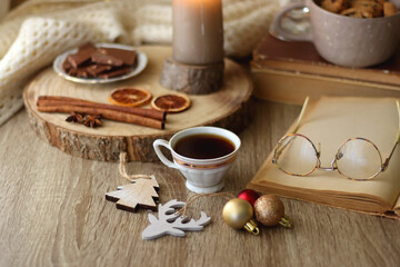 Cup of tea or coffee, various sweets and spices, Christmas decorations, comfy blanket, books and glasses. Selective focus.