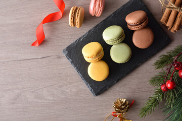 Assorted macaroons on wooden table with Christmas decoration top view