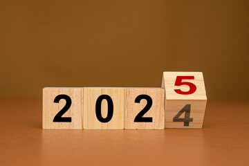 Wooden cubes with the letters 2024 changed to 2025 on a table - obrazy, fototapety, plakaty