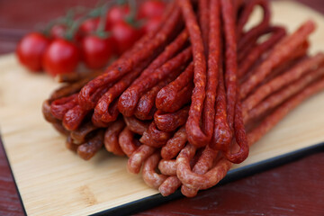 Tasty dry cured sausages (kabanosy) on wooden table, closeup