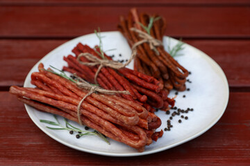 Tasty dry cured sausages (kabanosy) and spices on wooden table