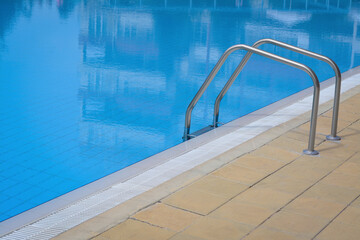 Outdoor swimming pool with handrails at resort on sunny day