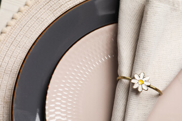 Fabric napkin and decorative ring for table setting on gray plate, closeup