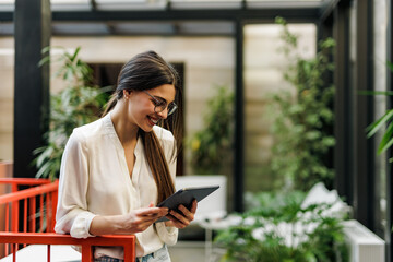 Obraz premium Businesswoman standing at the office, using a digital tablet.